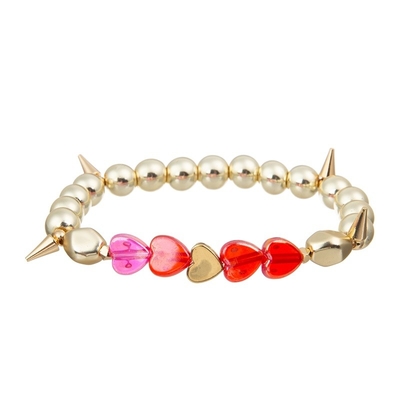 El metal del color oro gotea el corazón del rosa que la pulsera hecha a mano fijó para la muchacha como regalo
